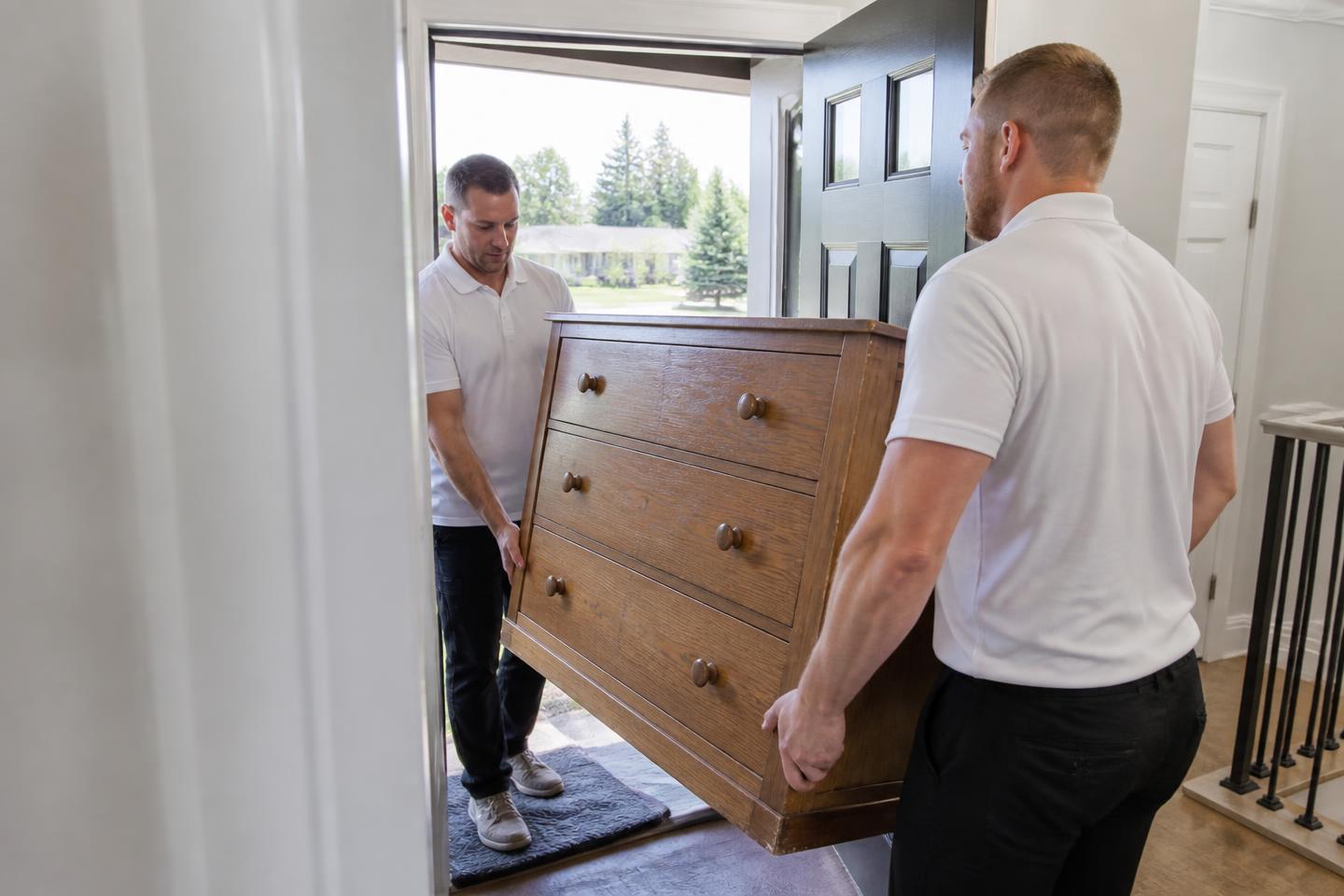 Movers carrying an unwanted dresser out of a Northern Colorado home